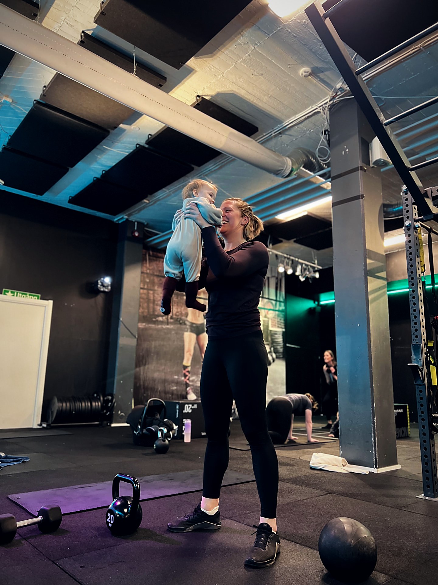 Mamma lyfter upp sin bebis under ett MAMMA-pass på Hitness i Danderyd